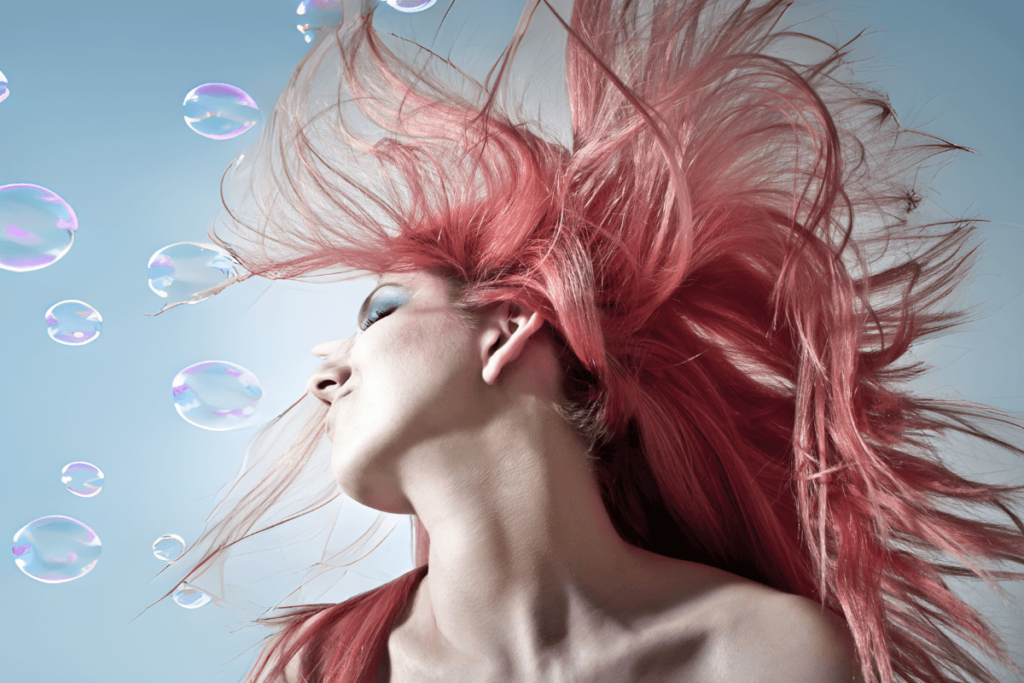 Eine Frau mit rötlichen Haaren schwingt ihren Kopf zur Seite. Auf der Seite hat es Bubbles.