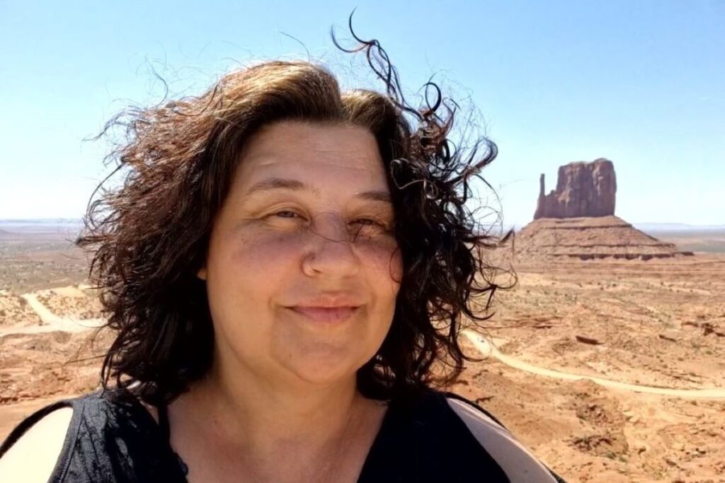 Eine Frau macht ein Selfie im Monument Valley. Der Wind zerzaust ihr Haar.